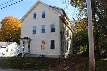 a view of a house with a yard and large tree