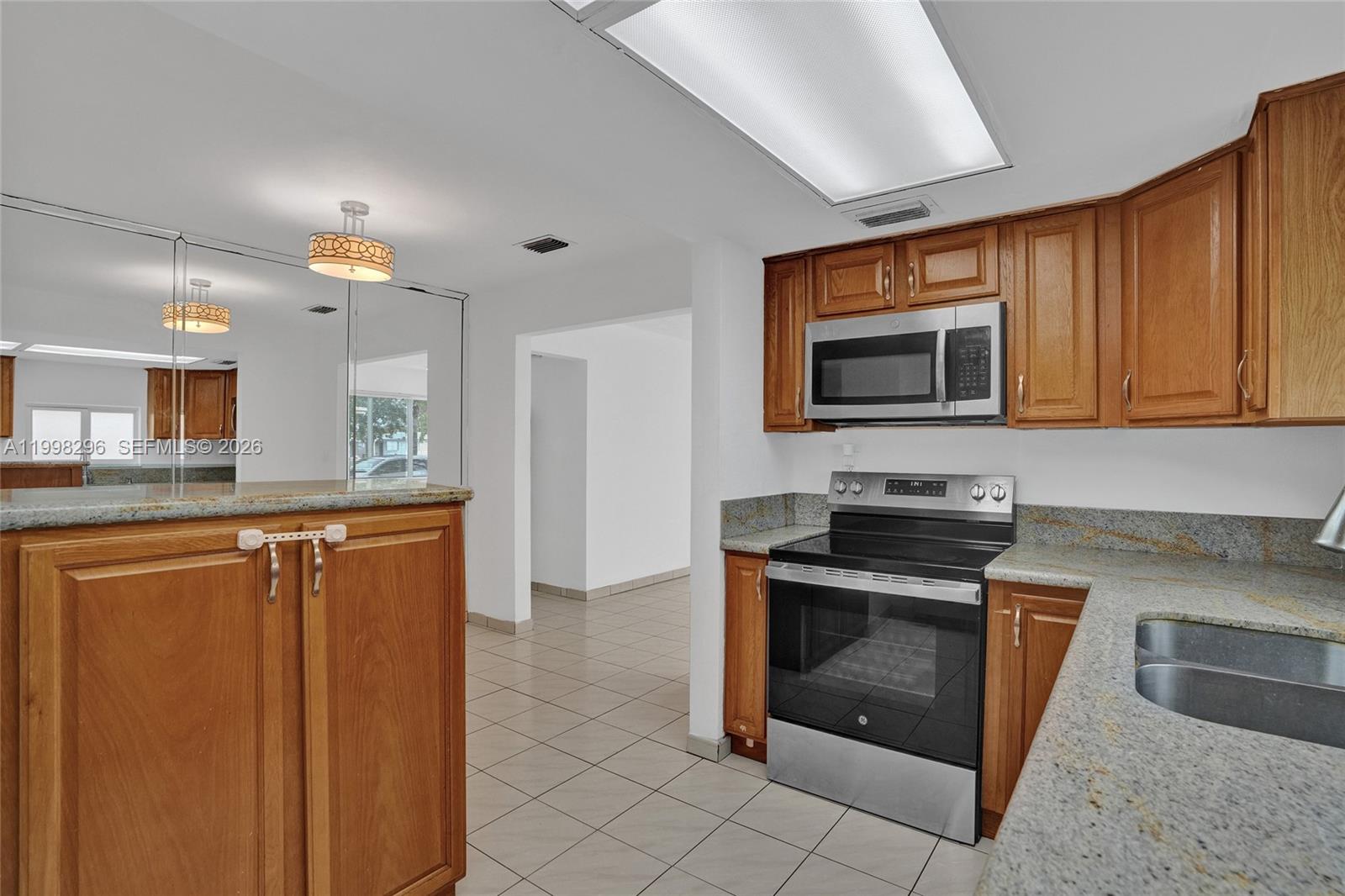 877 West 33rd Street Hialeah, FL 33012 - Photo 26 of 59 a kitchen with stainless steel appliances granite countertop a stove a microwave and a sink