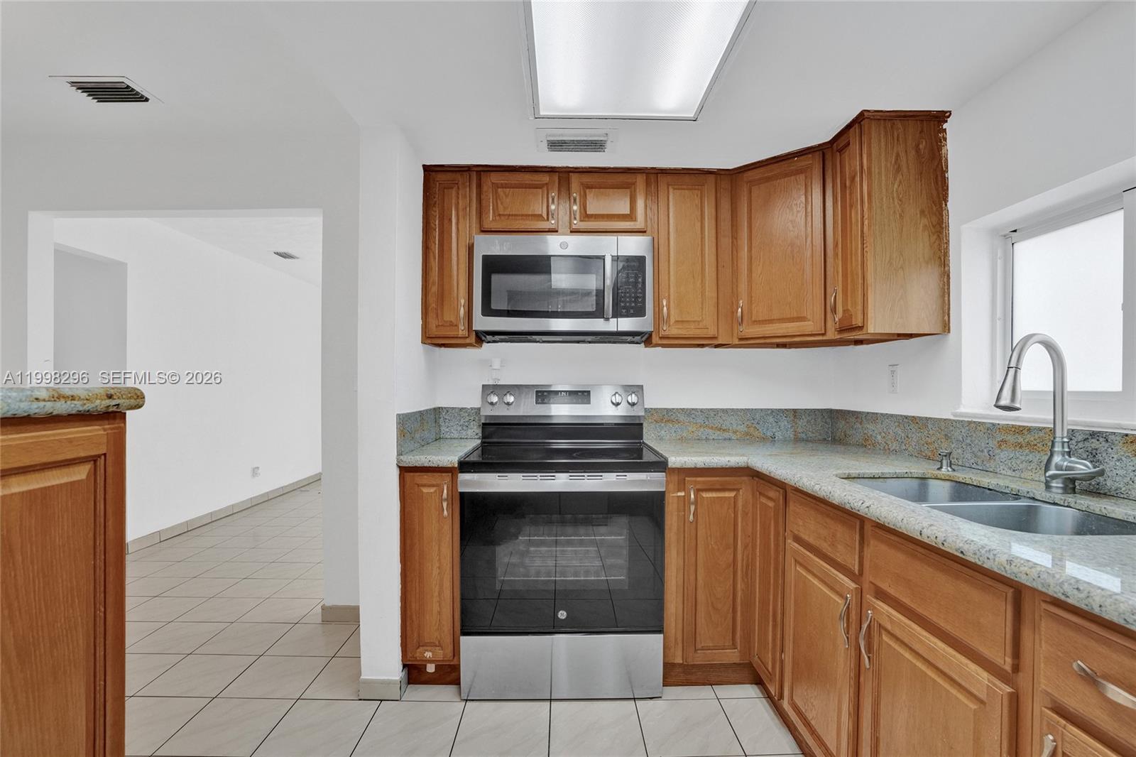 877 West 33rd Street Hialeah, FL 33012 - Photo 27 of 59 a kitchen with granite countertop a stove top oven microwave and cabinets