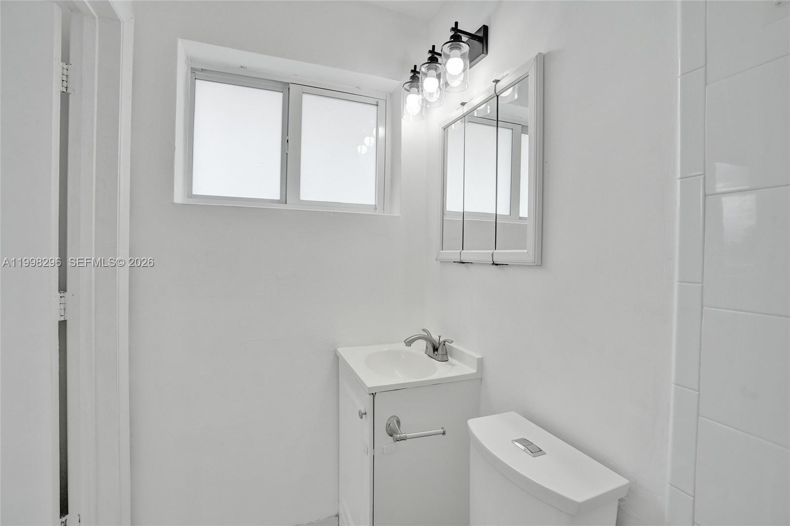 877 West 33rd Street Hialeah, FL 33012 - Photo 36 of 59 a bathroom with a sink a mirror and a toilet