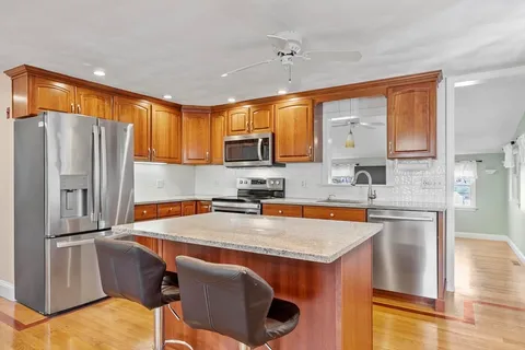 a kitchen with stainless steel appliances granite countertop a refrigerator a sink a stove and a microwave