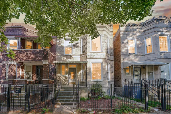 a front view of a building with glass windows and plants