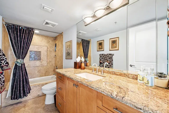 a bathroom with a granite countertop sink a toilet a mirror and shower