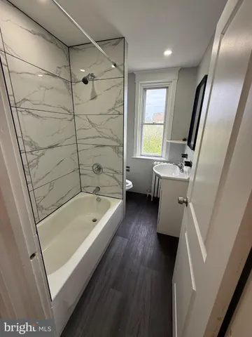 a bathroom with a tub shower a sink and a toilet