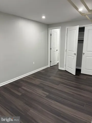 a view of an empty room with wooden floor and closet