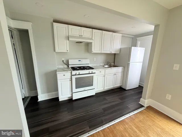 a kitchen with white cabinets and a wooden floor