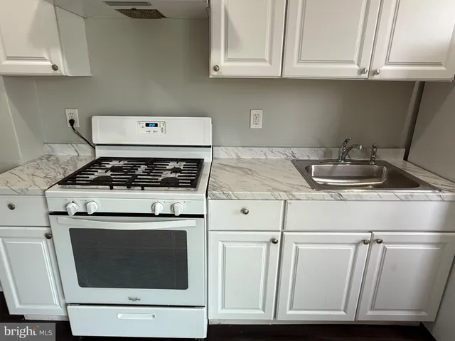 a kitchen with granite countertop white cabinets and a stove