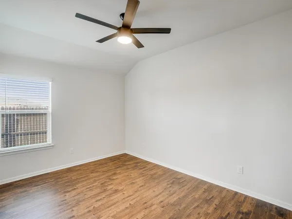 an empty room with wooden floor fan and windows