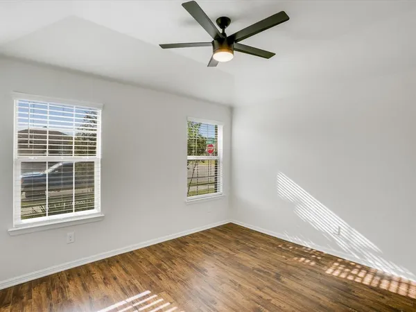 a view of empty room with wooden floor and fan
