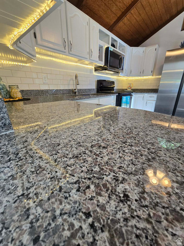 259 14th Street Ogden, UT 84404 - Photo 13 of 21 Kitchen featuring speckled countertops, white subway tile backsplash, white cabinetry with dark hardware, and a built-in microwave