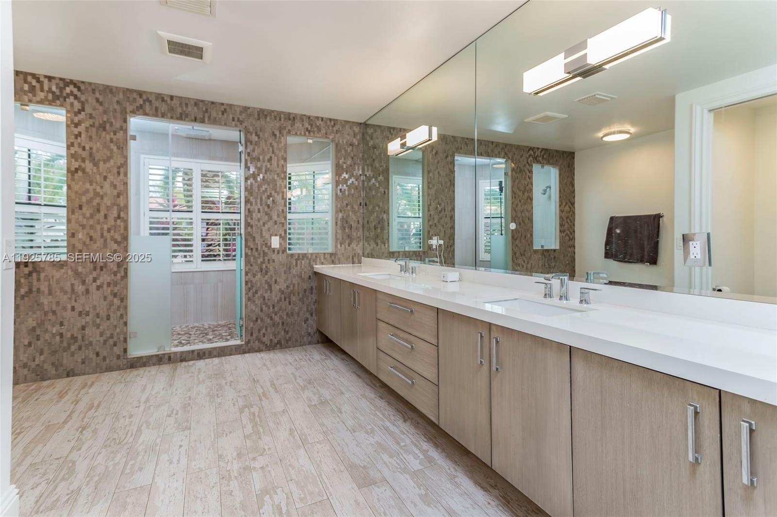 1962 Southwest 185th Avenue Miramar, FL 33029 - Photo 26 of 55 a bathroom with a double vanity sink a large mirror and shower