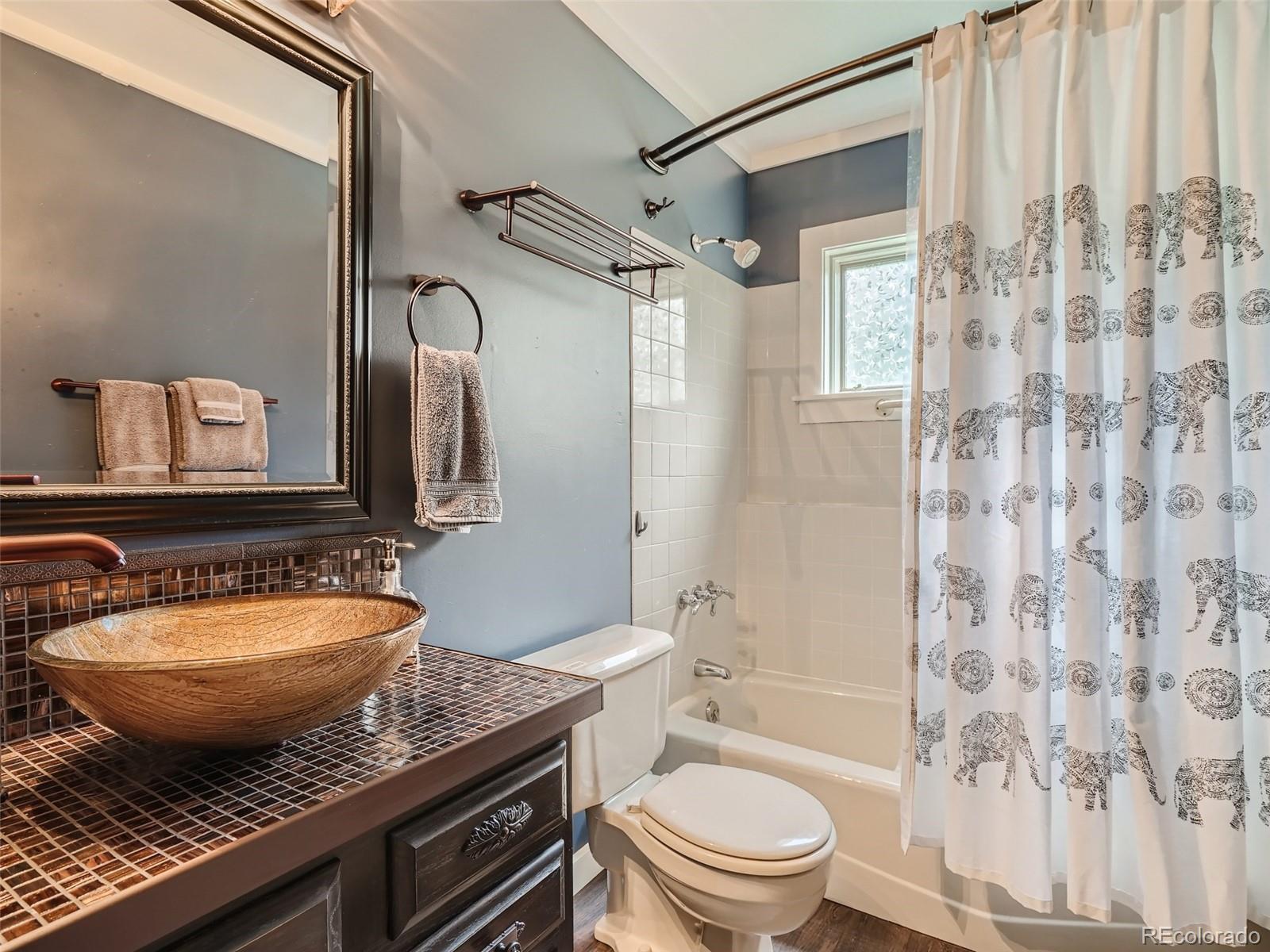 4387 Witter Gulch Road Evergreen, CO 80439 - Photo 22 of 31 a bathroom with a granite countertop sink toilet a mirror a bathtub and shower