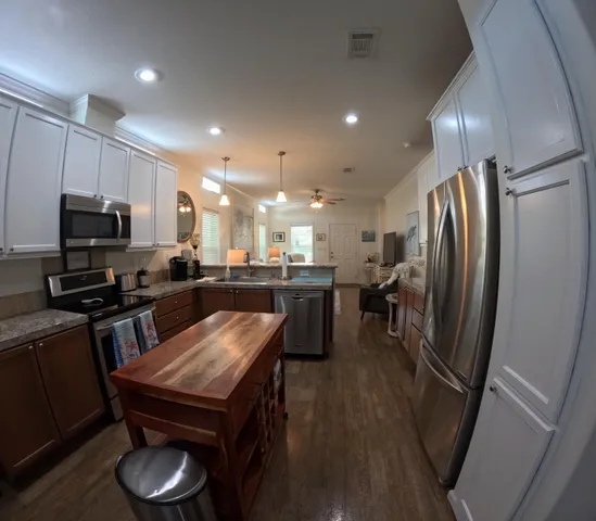 a kitchen with stainless steel appliances granite countertop a refrigerator a sink dishwasher a stove and a sink