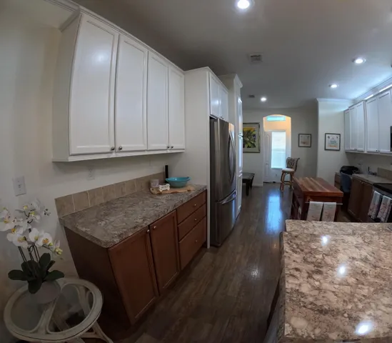 a kitchen with stainless steel appliances granite countertop a refrigerator a stove and a sink with wooden floor