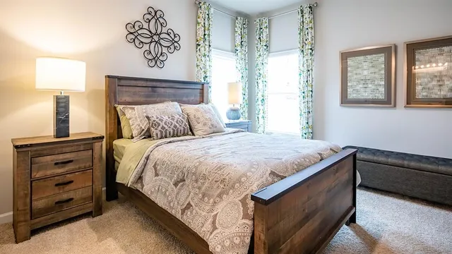 a bedroom with a bed a mirror on dresser and a window