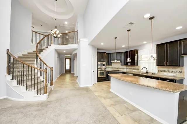 a view of a kitchen with kitchen island stainless steel appliances a stove a sink a center island and living room view