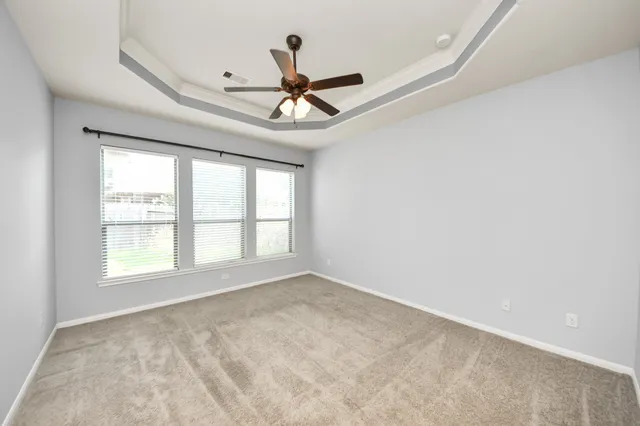 an empty room with a ceiling fan and windows
