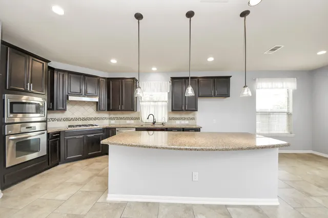 a kitchen with kitchen island a counter top stainless steel appliances and cabinets
