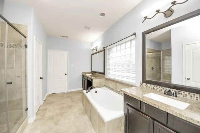 a bathroom with a granite countertop sink a mirror and a bathtub