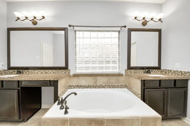 a bathroom with a tub a sink and a window