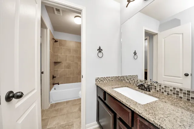 a bathroom with a granite countertop sink a mirror and shower