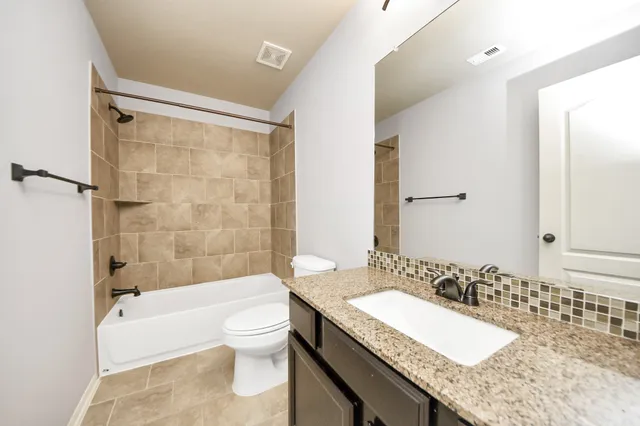 a bathroom with a granite countertop tub sink toilet and mirror
