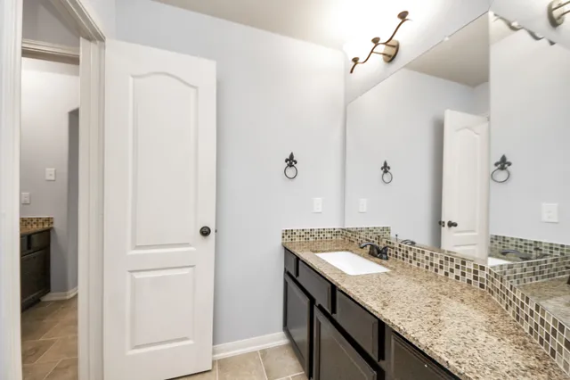 a bathroom with a granite countertop sink and a mirror