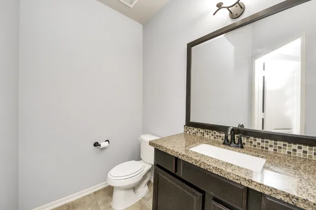 a bathroom with a granite countertop sink a toilet and a mirror