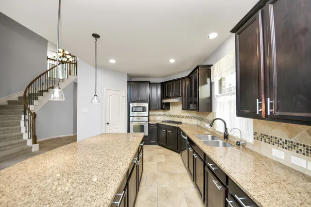 a large kitchen with kitchen island granite countertop a sink and a refrigerator