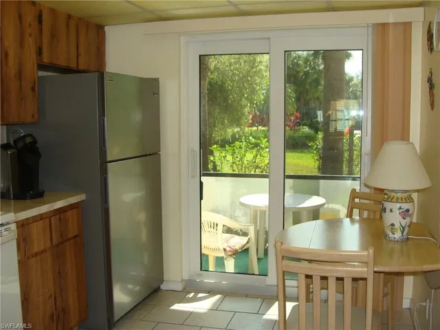 a kitchen with a refrigerator a stove a sink and a dining table with garden view