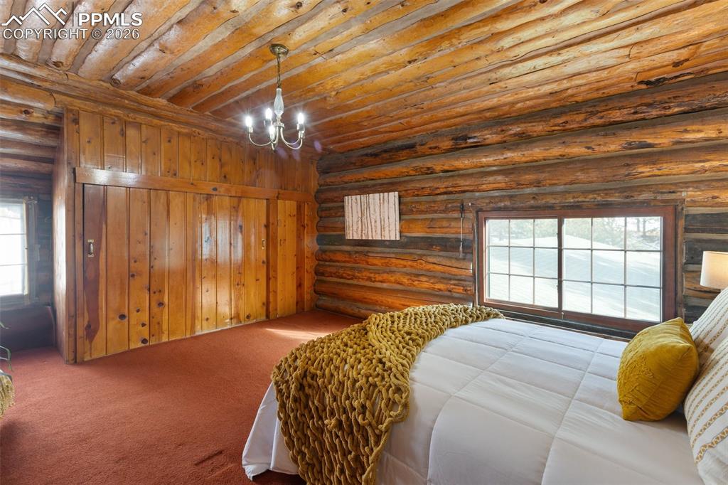 2300 Rampart Range Road Woodland Park, CO 80863 - Photo 28 of 45 a bedroom with a bed and a chandelier