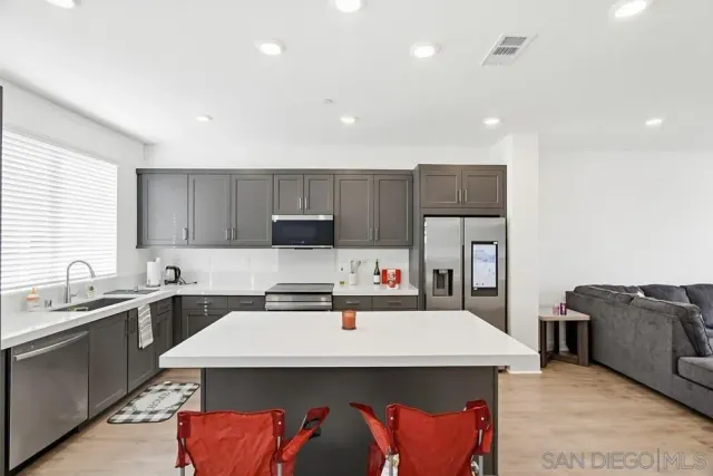 a kitchen with kitchen island stainless steel appliances a sink and a refrigerator