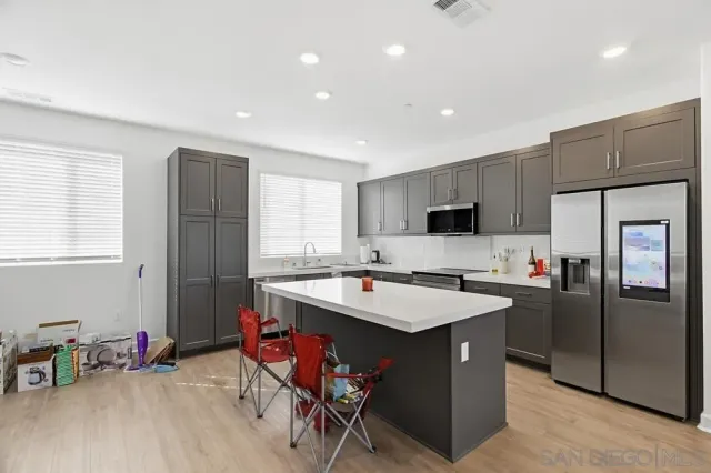 a kitchen with a refrigerator a stove top oven a sink dishwasher and a dining table with wooden floor