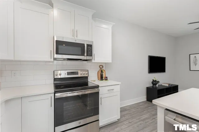 a kitchen with cabinets stainless steel appliances and wooden floor