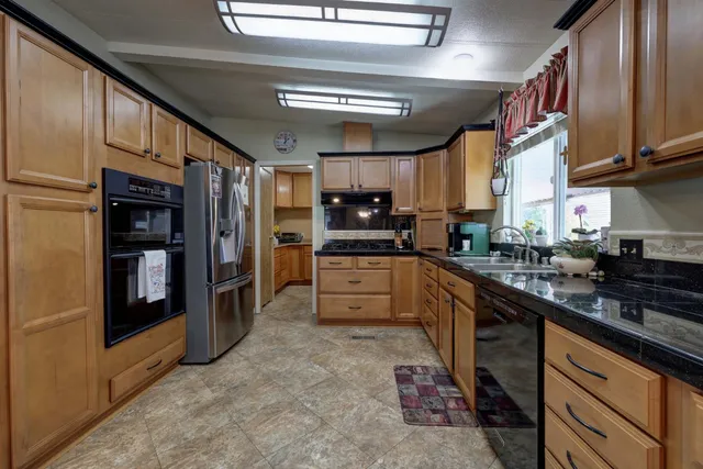 a kitchen with granite countertop a sink cabinets stainless steel appliances and a window