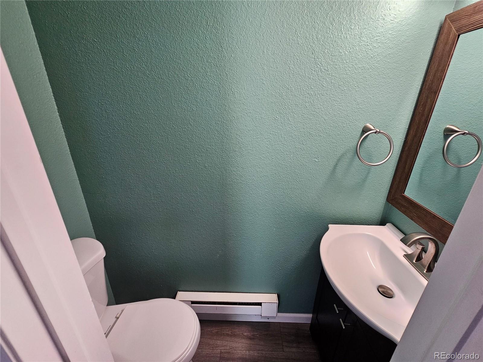 16985 Sage Crest Road Peyton, CO 80831 - Photo 5 of 25 a white toilet sitting next to a bathroom sink and a mirror