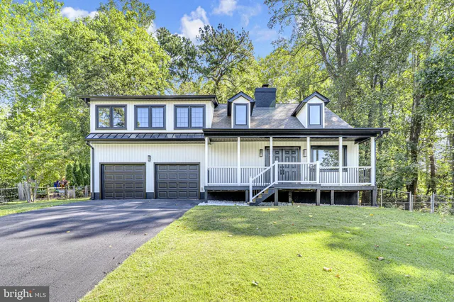 a front view of a house with a yard balcony and a large tree