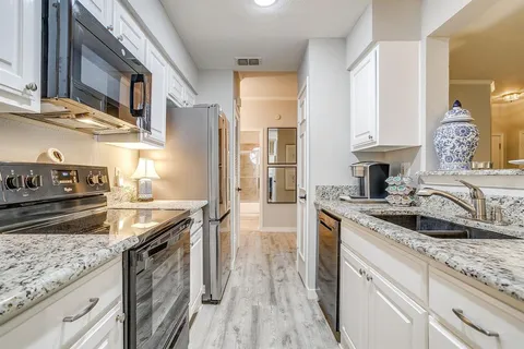 a kitchen with granite countertop a sink stainless steel appliances and cabinets