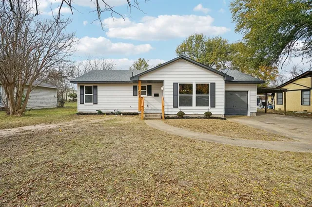 a view of a house with a yard and large tree