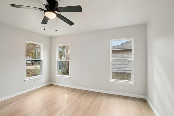 a view of an empty room with a window and wooden floor