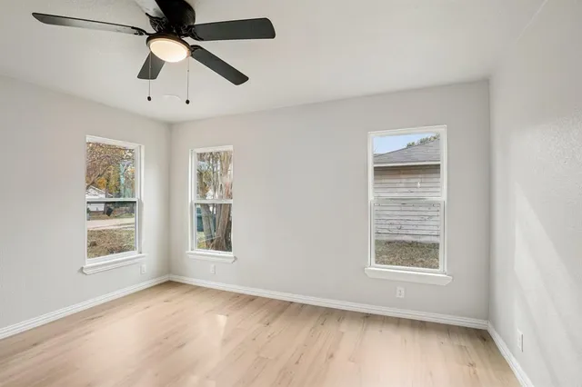 a view of an empty room with a window and wooden floor