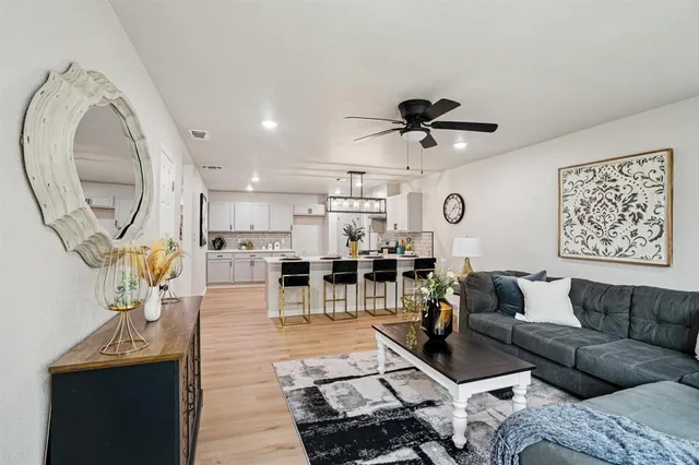 a living room with furniture a clock and a view of kitchen