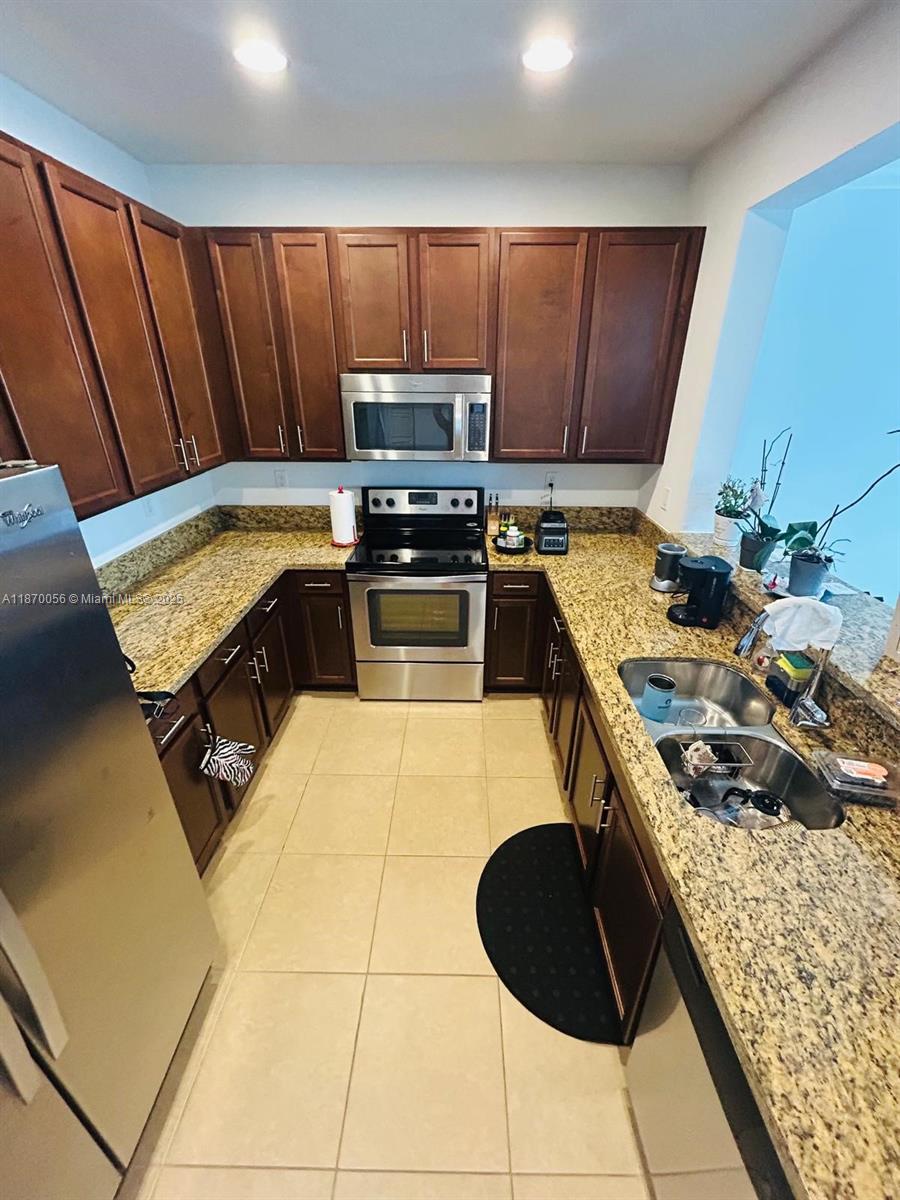 819 Southwest 147th Avenue, Unit 1405 Pembroke Pines, FL 33027 - Photo 30 of 31 a kitchen with a stove a sink and a microwave