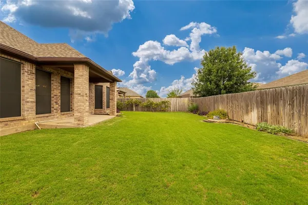 a view of a house with backyard and wooden fence