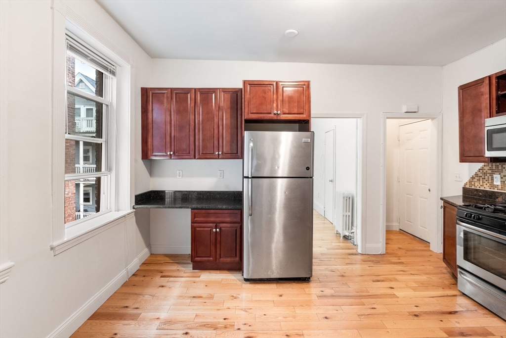 80-84 Shepton Street, Unit 803 Boston, MA 02124 - Photo 3 of 16 a kitchen with stainless steel appliances granite countertop a refrigerator and a stove top oven