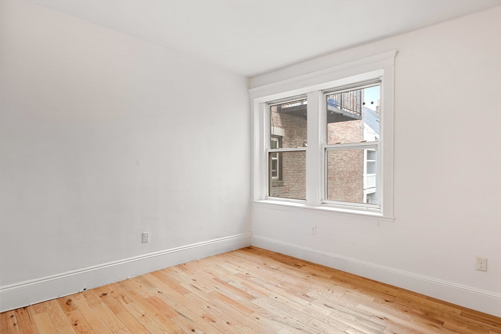 80-84 Shepton Street, Unit 803 Boston, MA 02124 - Photo 8 of 16 an empty room with wooden floor and windows