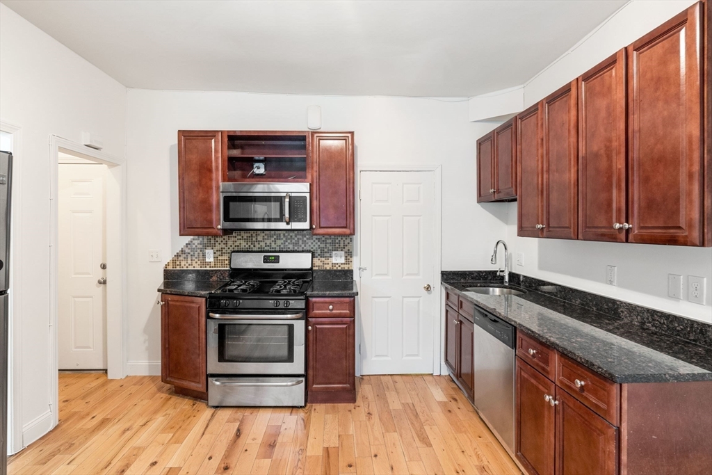 80-84 Shepton Street, Unit 803 Boston, MA 02124 - Photo 9 of 16 a kitchen with stainless steel appliances a stove a sink and wooden floor