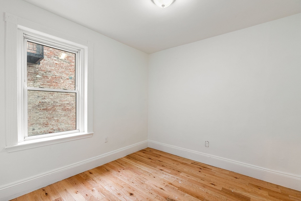 80-84 Shepton Street, Unit 803 Boston, MA 02124 - Photo 10 of 16 an empty room with wooden floor and windows
