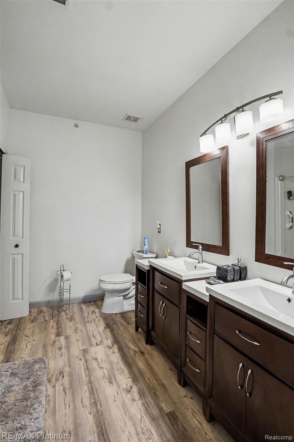 10217 Crossview Trail Howell, MI 48855 - Photo 21 of 26 Spacious bathroom featuring a dual vanity with dark wood cabinetry, integrated white sinks, and chrome faucets