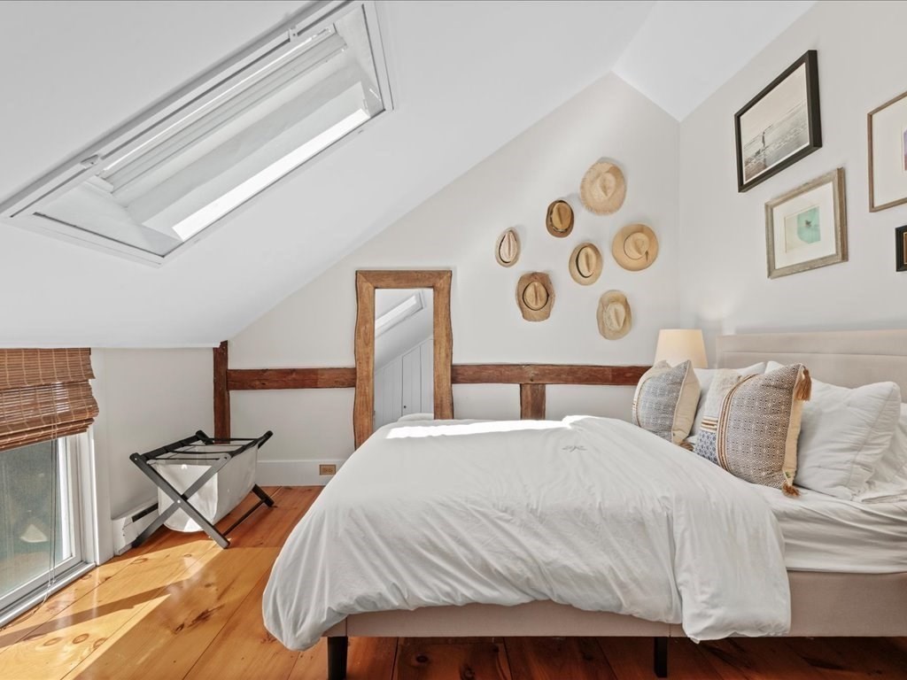 144 Old County Road Sandwich, MA 02537 - Photo 25 of 42 a bed sitting in a bedroom next to a chair and a chandelier